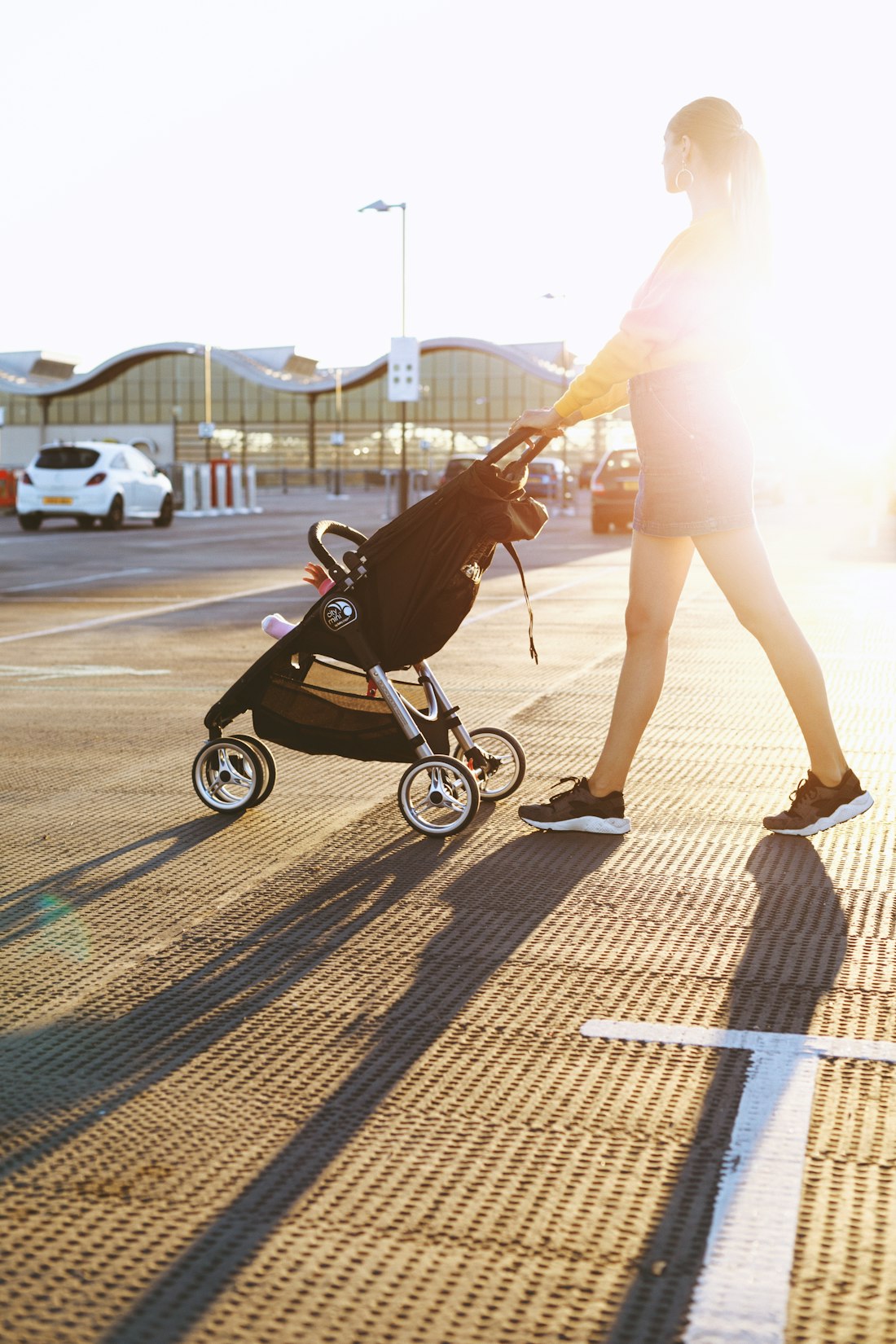 A mother walking with a stroller in the evening sun