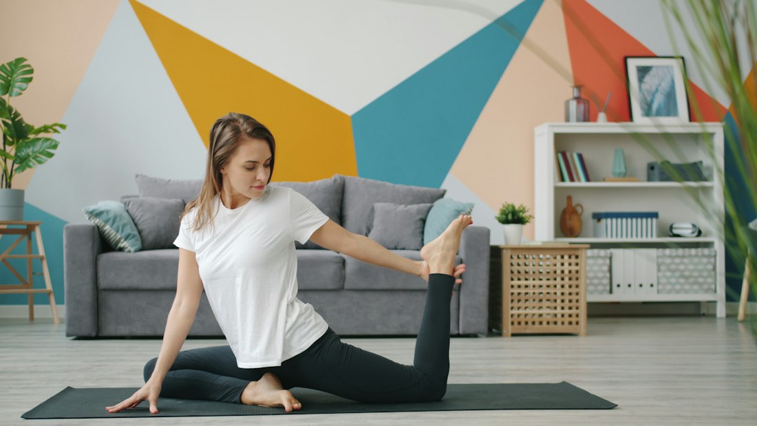 A woman stretching on a yoga mat in her living room